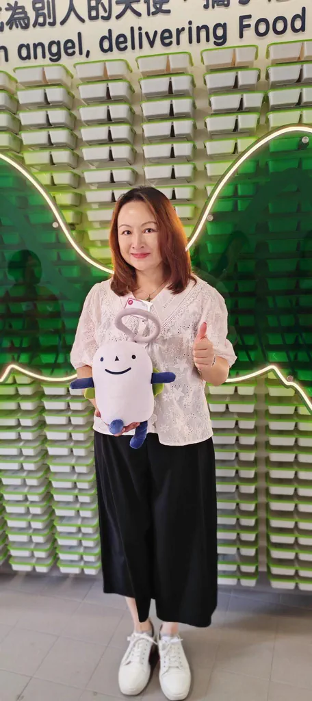 FreeComm director Candy Chui at Food Angel's new facility holding the mascot